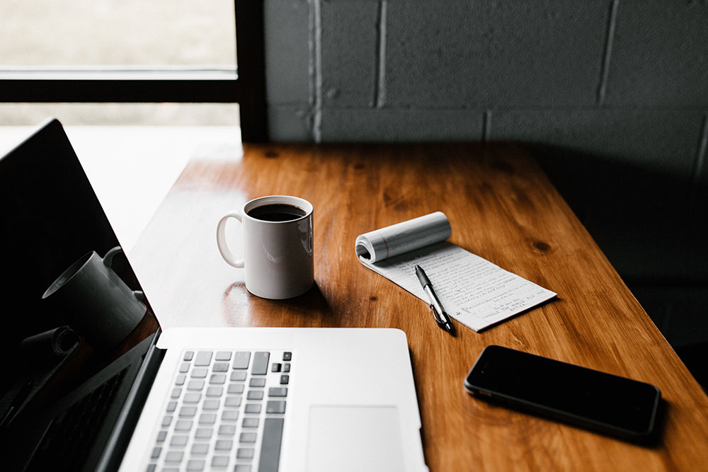 desk with laptop, coffee, smart phone, and medicare checklist